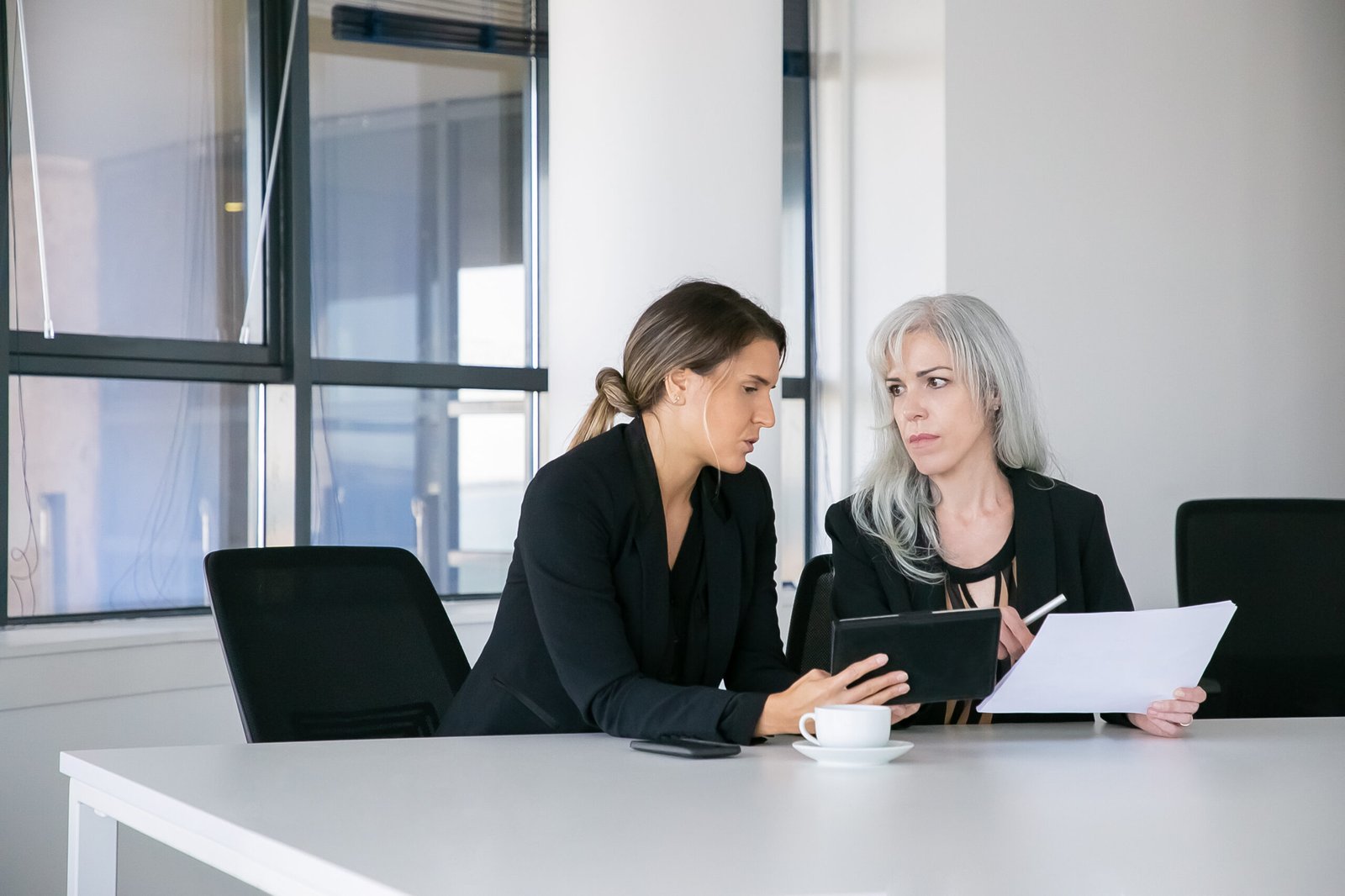 Focused female colleagues discussing and analyzing reports